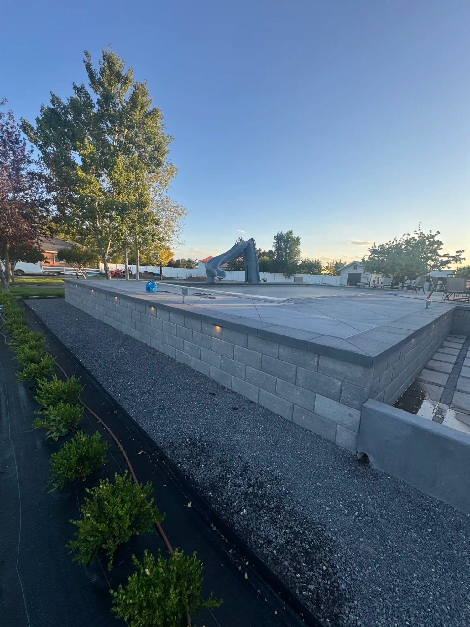 CMU stone retaining wall with pool deck outdoor living space by EC Landscaping in Mantua Utah