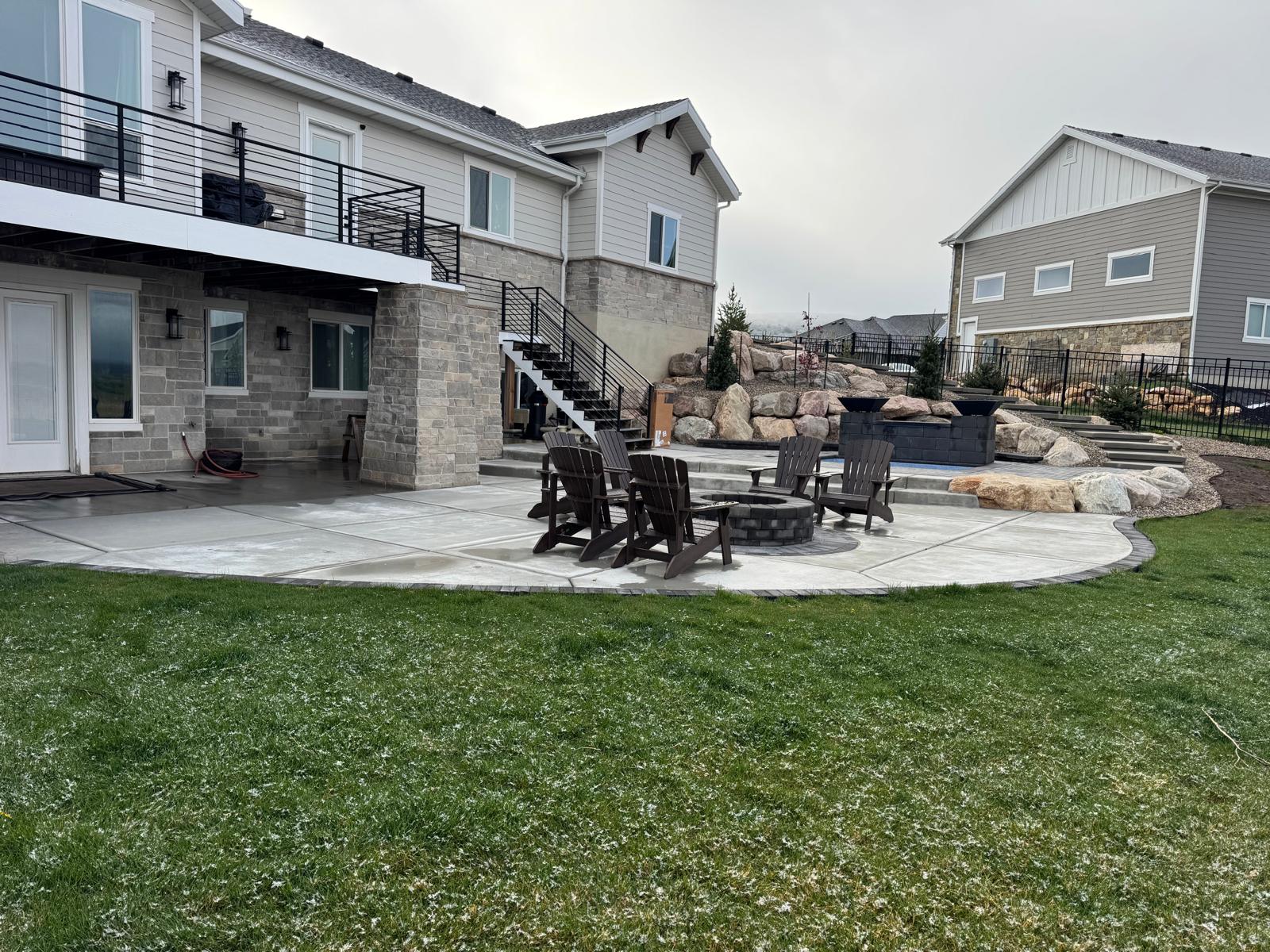 Backyard paver patio fire pit with lush green lawn and privacy landscaping, Northern Utah
