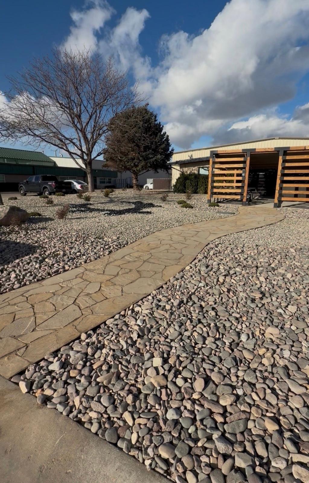 Flagstone walkway with river rock fill and wood pergola structure in backyard landscape, Northern Utah