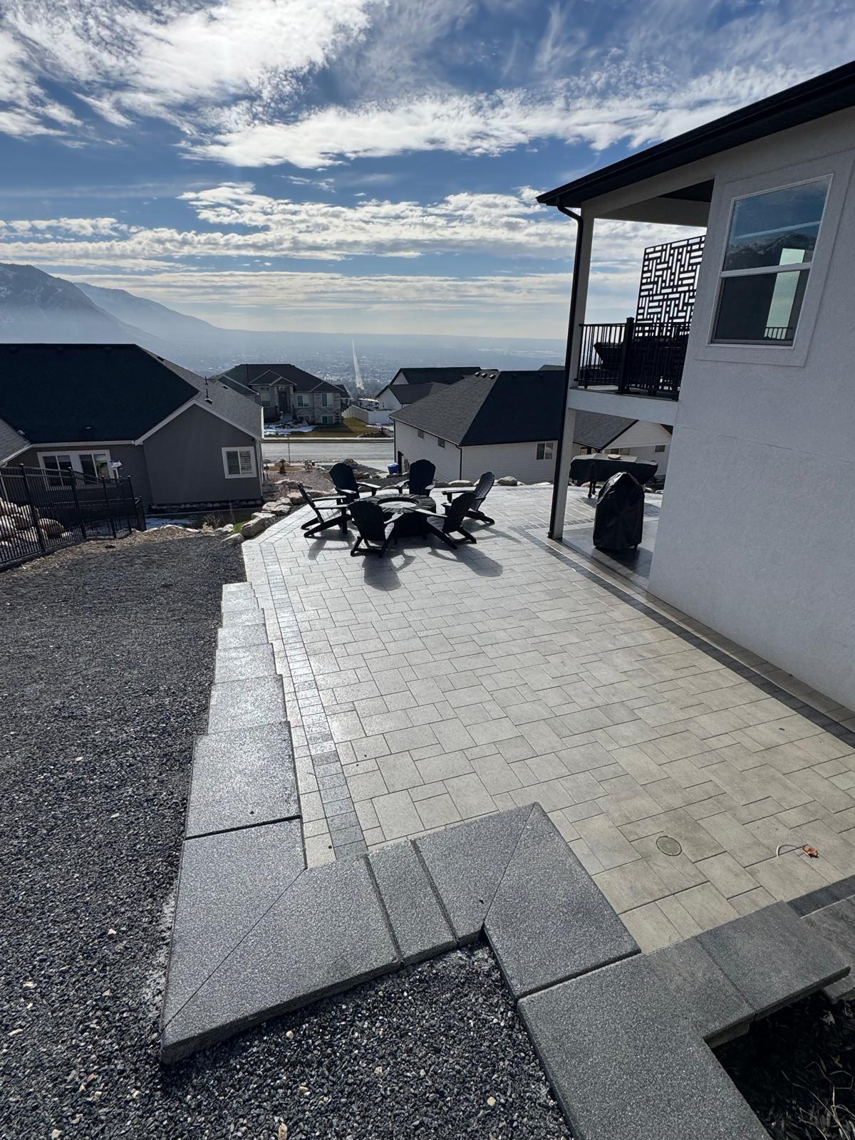 Paver patio fire pit with Adirondack chairs and valley city view at dusk, North Ogden Utah