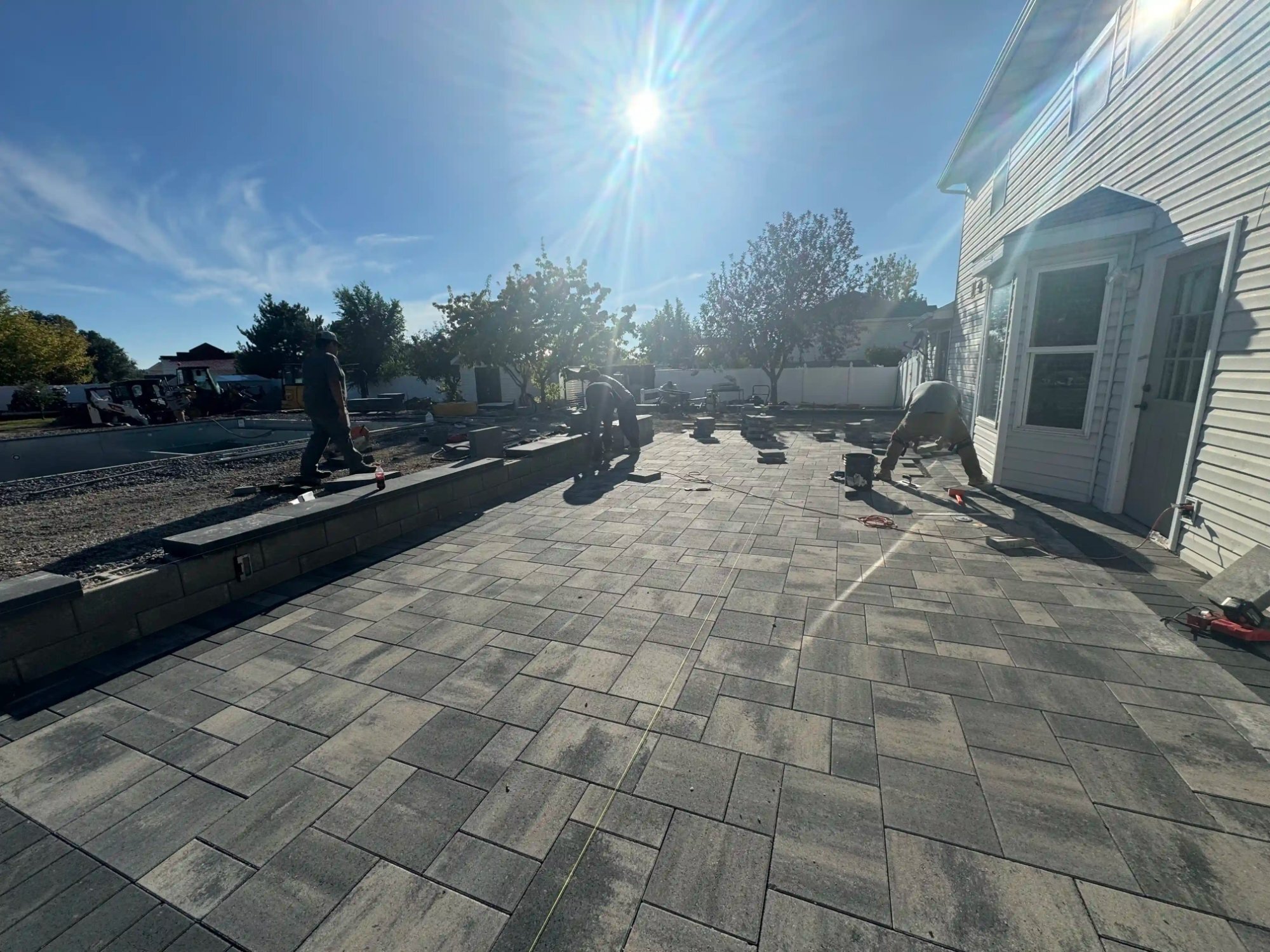 Crew installing a dark charcoal paver patio